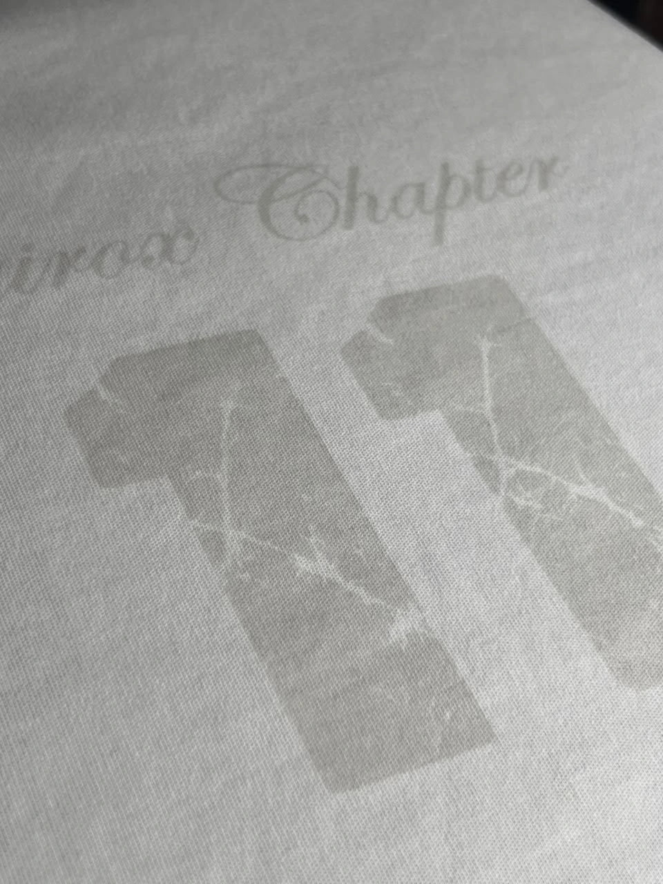 QAIROX Chapter Tee off-white close-up — subtle tone-on-tone Qairox Chapter 11 graphic detail, premium screen print on cotton interlock