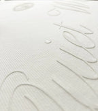 Close-up of a white textured mattress or bedding surface with embossed script lettering.