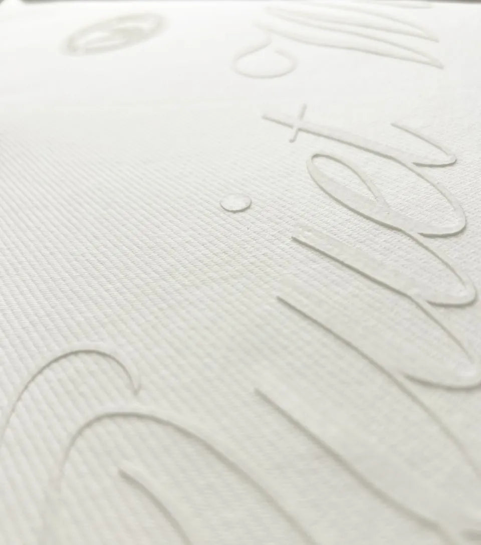 Close-up of a white textured mattress or bedding surface with embossed script lettering.